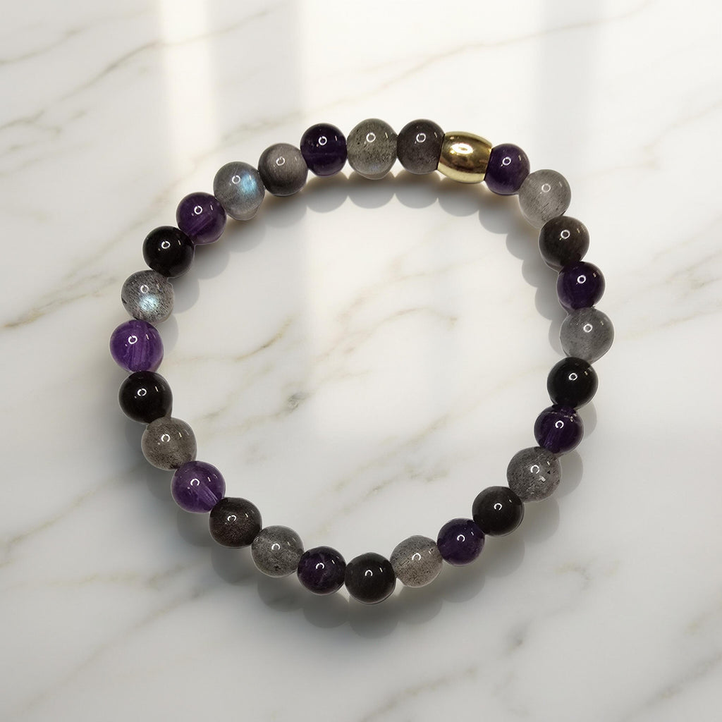 "Bracelet lithothérapie douleur psychique et mentale avec perles de labradorite irisée, améthyste violette et obsidienne argentée sur fond neutre"
