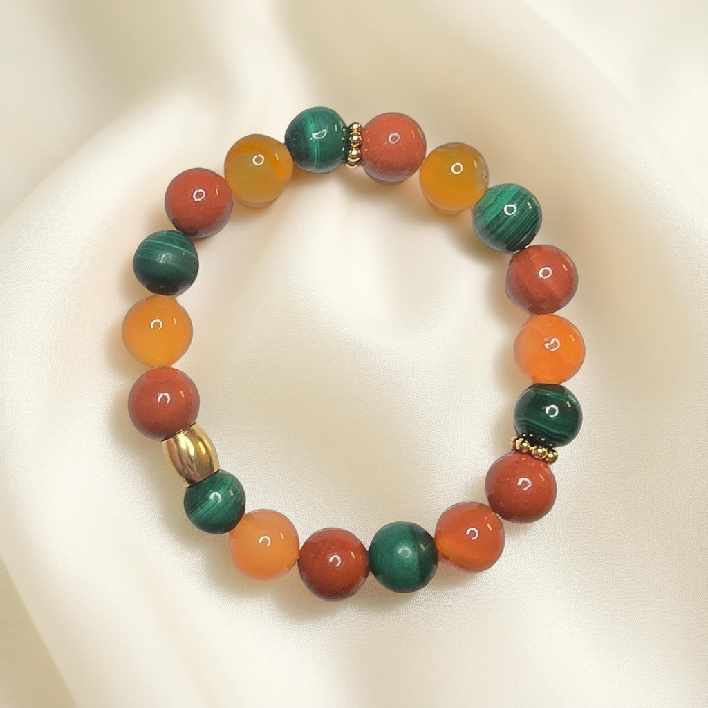 "Bracelet lithothérapie digestion paresseuse avec perles de cornaline orange, jaspe rouge et malachite verte sur fond neutre"