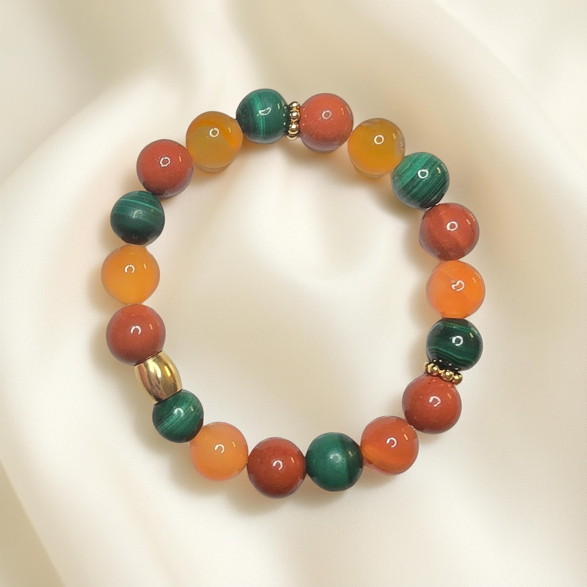 "Bracelet lithothérapie digestion paresseuse avec perles de cornaline orange, jaspe rouge et malachite verte sur fond neutre"